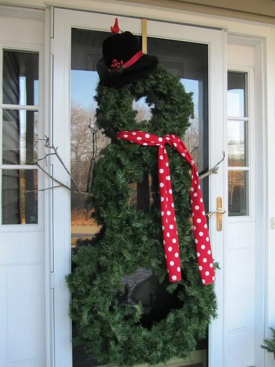 a pretty evergreen snowman made of wreaths, with a polka dot scarf, a black hat and some branch hands is a cool idea