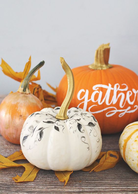 an arrangement of Thanksgiving pumpkins in white, orange, with calligraphy and simple botanical patterns done with a sharpie