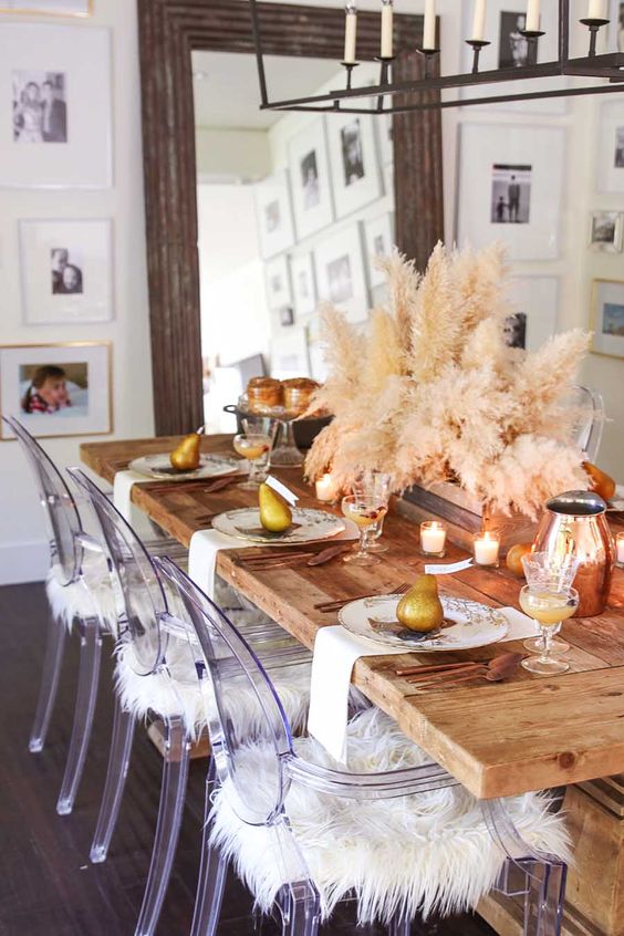 a relaxed boho Thanksgiving tablescape with printed plates, white napkins, candles, a pampas grass centerpiece and copper jugs