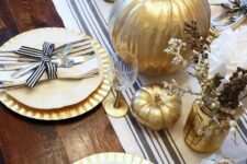 17 a chic rustic Thanksgiving tablescape with a striped runner, gold chargers, striped napkins, gilded pumpkins and faux branches