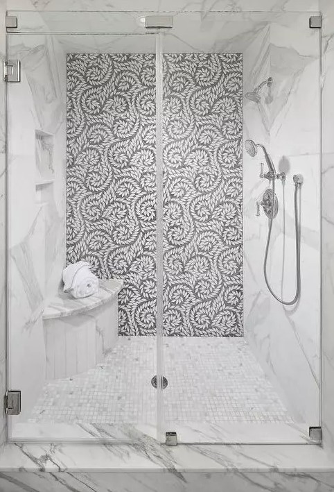 a gorgeous grey and white shower with a small rounded bench in the corner that doesn't take much space
