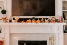 19 a lovely Thanksgiving mantel with bold leaves, candles, pinecones, small pumpkins on the mantel and larger ones next to the fireplace