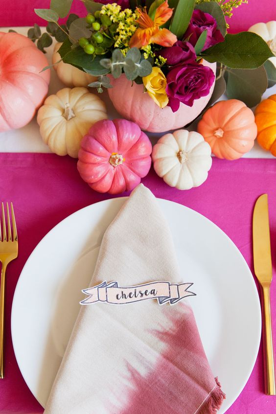 a bright Thanksgiving tablescape with a hot pink tablecloth, bold pumpkins and bold blooms, dip dyed napkins