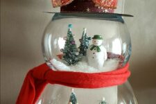 20 a creative snowman decoration made of fish bowls and with snowy wintry scenes inside, with a top hat and a scarf