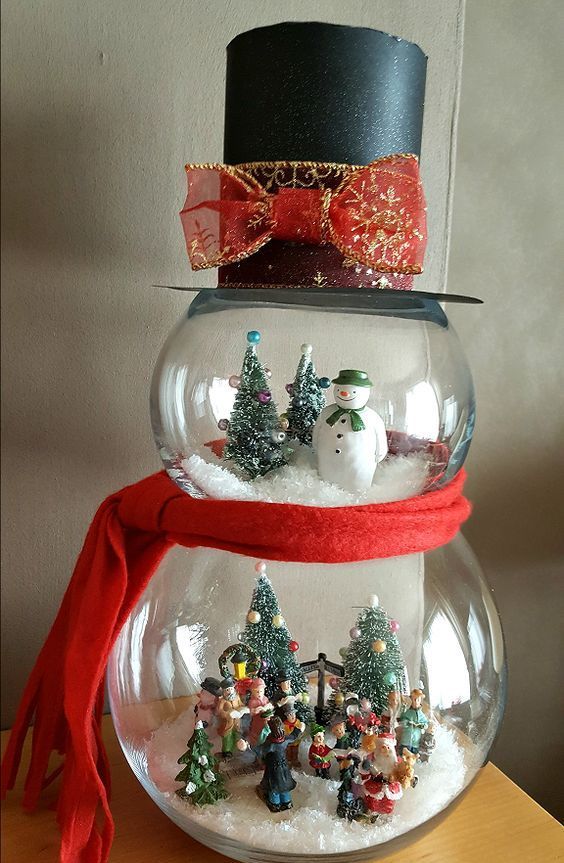 a creative snowman decoration made of fish bowls and with snowy wintry scenes inside, with a top hat and a scarf