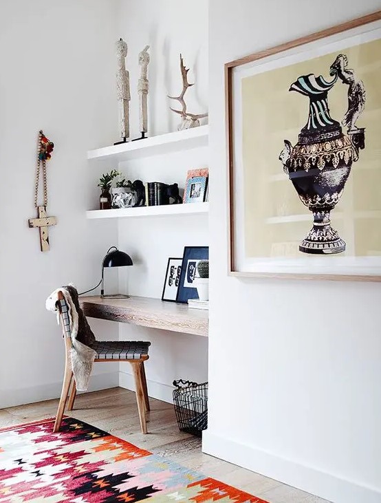a small modern awkward nook with built in shelves, a stained built in desk, a woven chair, antlers, books and artworks and a basket