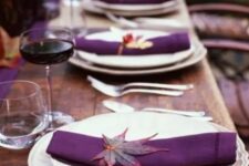 21 a chic Thanksgiving tablescape with an uncovered table, a purple table runner and napkins plus deep purple candles and bold fall leaves is amazing