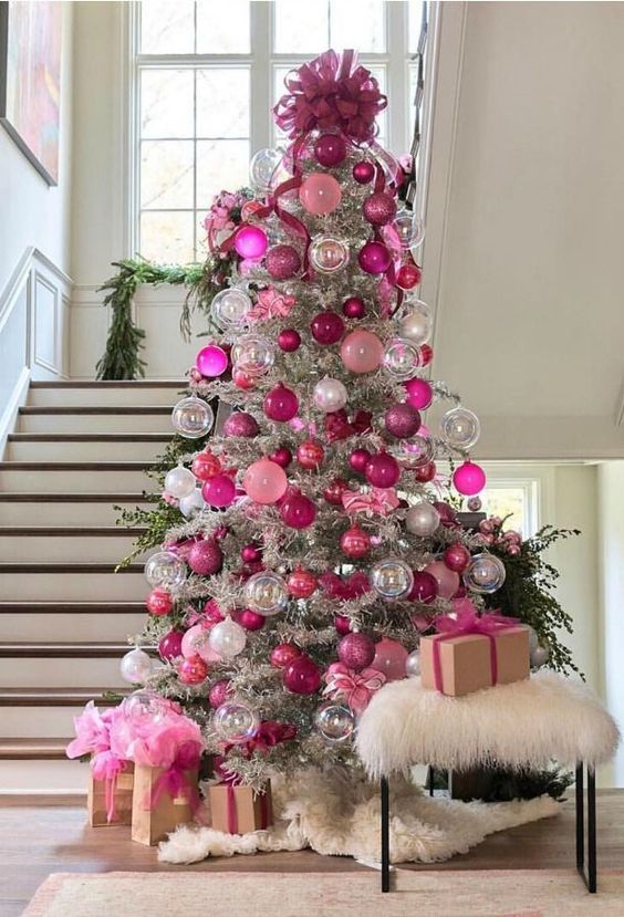 a silver Christmas tree decorated with clear, hot pink, fuchsia and white ornaments, topped with a large pink ribbon bow