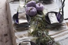 22 a creative and laid-back Thanksgiving tablescape with a linen striped tablecloth, a greenery runner, lilac pumpkins and lilac bottles with greenery
