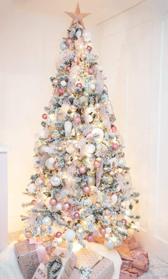 a flocked Christmas tree decorated with neutral, pink, silver ornaments, blush ribbon and a pink star topper