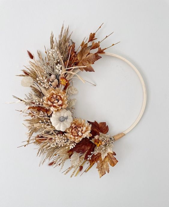 a boho Thanksgiving wreath of an embrodiery hoop, with dried grasses, faux blooms and leaves, some twigs and berries