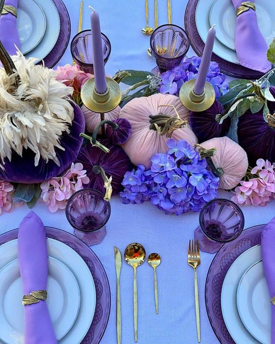 a glam Thanksgiving tablescape with a lilac tablecloth and napkins, lilac candles, purple, deep purple and violet blooms and gilded cutlery