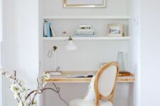 23 a small nook with built-in shelves and a desk, a white chair, an artwork and a pretty lamp is comfy for working