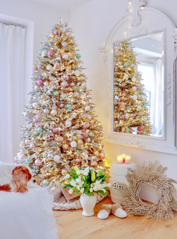 a flocked Christmas tree decorated with white, gold, pastel pink and green ornaments plus some metallic ones