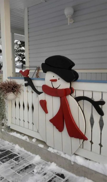 a plaque snowman attached to the porch fence is a lovely idea to add cuteness to your outdoor Christmas decor