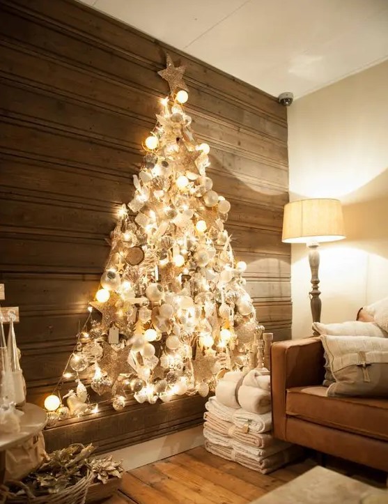 a shiny wall mounted Christmas tree made with lights on the contour and with lots of silver, pearly and white ornaments inside