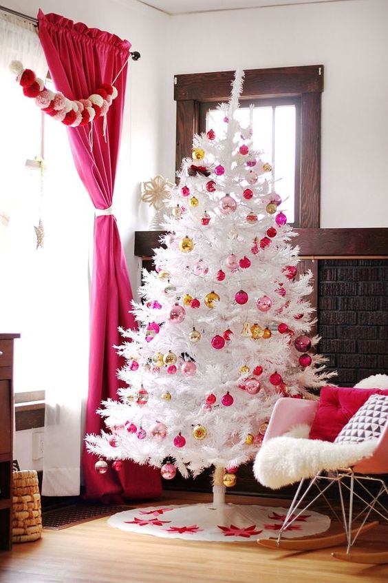 a white Christmas tree decorated with light and hot pink and gold ornaments is a stylish and catchy decoration
