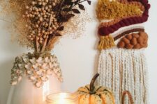 26 a bright fall woven hanging, a pumpkin and a candle, a vase with dried branches and berries for boho Thanksgiving decor