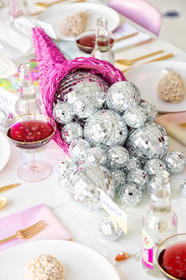 a glam Thanksgiving centerpiece of a hot pink cornucopia filled with silver disco balls is a fun and cool idea