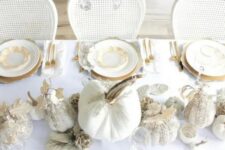 26 a refined white and gold Thanksgiving tablescape with white embellished pumpkins, white leaves, gold chargers and cutlery plus a crystal chandelier over the table
