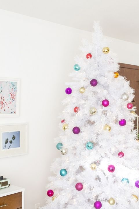 a white Christmas tree decorated with silver, gold, mint green, fuchsia and hot pink ornaments looks fun and bold