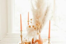 27 a neutral boho Thanksgiving centerpiece of wooden pumpkins, a terracotta vase and candles, dried grasses, lights and leaves