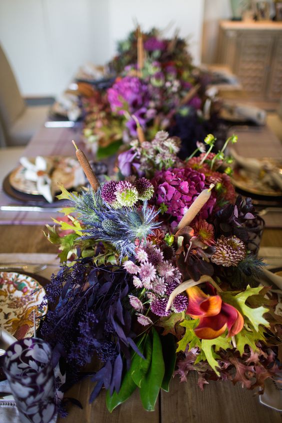 a refined and bold Thanksgiving centerpiece of purple, orange and fuchsia blooms, greenery, thistles and some foliage