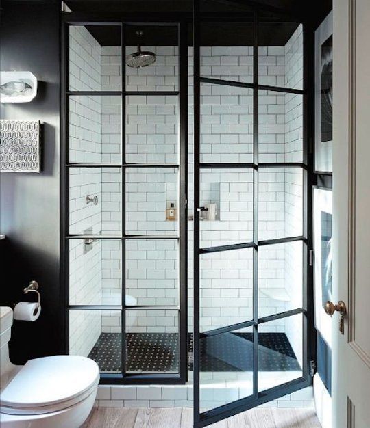a chic black and white bathroom with a shower with paned glass doors and black and white tiles cladding it