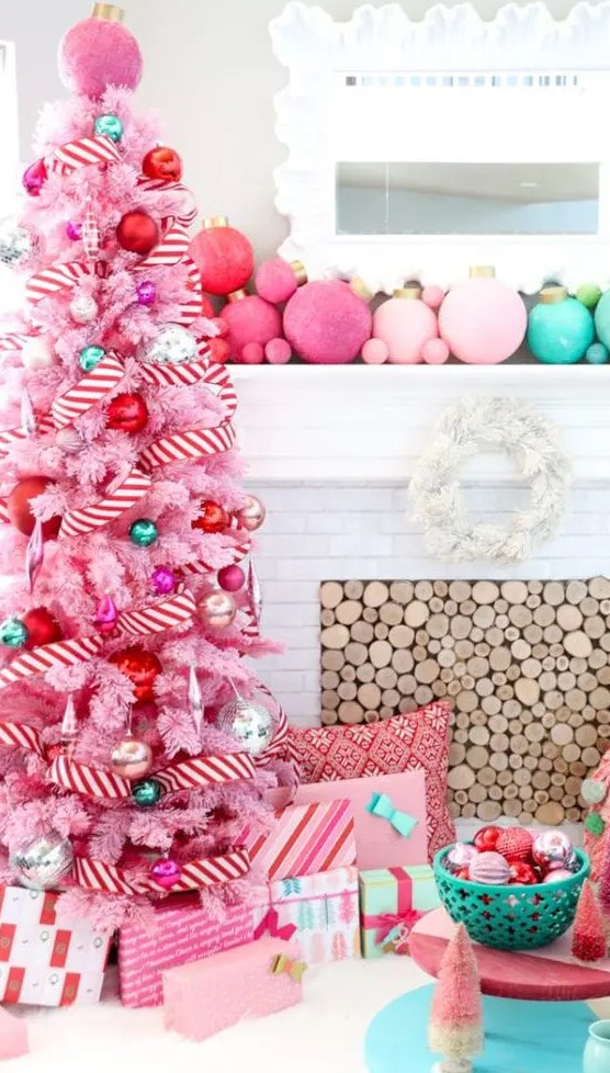 a pastel pink Christmas tree decorated with pink, red, green and silver ornaments and with a striped garland is pure fun and glam