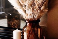 29 boho meets rustic Thanksgiving decor with woven pumpkins, a large brown vase with pampas grass and various candles