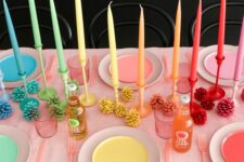 30 a rainbow Thanksgiving tablescape with bright plates and candles, bold pinecones and pink cutlery is very unusual