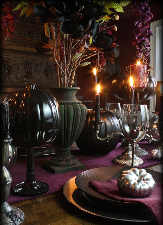 a refined Gothic tablescape for Thanksgiving   with purple linens, black plates, glasses and candles and some greenery