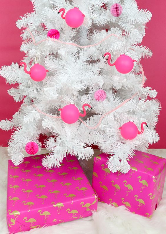 a white Christmas tree decorated with hot pink paper pompoms and flamingo-shaped ornaments is a fun idea for a tropical holiday space