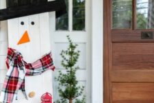 30 cozy and simple Christmas outdoor decor with a plywood snowman in a plaid scarf, with a top hat and red candle lanterns