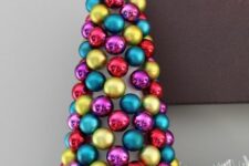 31 a colorful tabletop Christmas tree made o a cardboard cone and bright ornaments plus a silver star