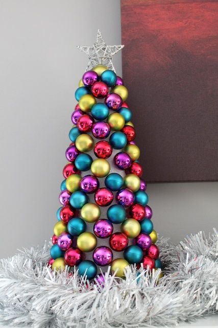 a colorful tabletop Christmas tree made o a cardboard cone and bright ornaments plus a silver star