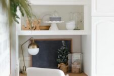 31 a tiny home office space in the kitchen, with just a small built-in desk, a white chair and a brass lamp plus a chalkboard