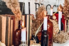 31 boho Thanksgiving decor with neutral pumpkins and dried blooms, white candles in dark apothecary bottles and vintage books