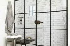 32 a vintage-inspired bathroom with white subway and graphite grey tiles, a shower space with black frame doors and a bench inside