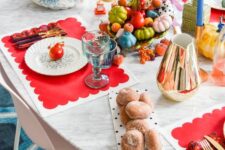 33 a super colorful Thanksgiving table setting with red placemats, blue candles, colorful faux veggies and blue glasses