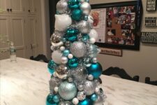 33 a tabletop Christmas tree made of white, white and blue Christmas ornaments, with a silver snowflake on top