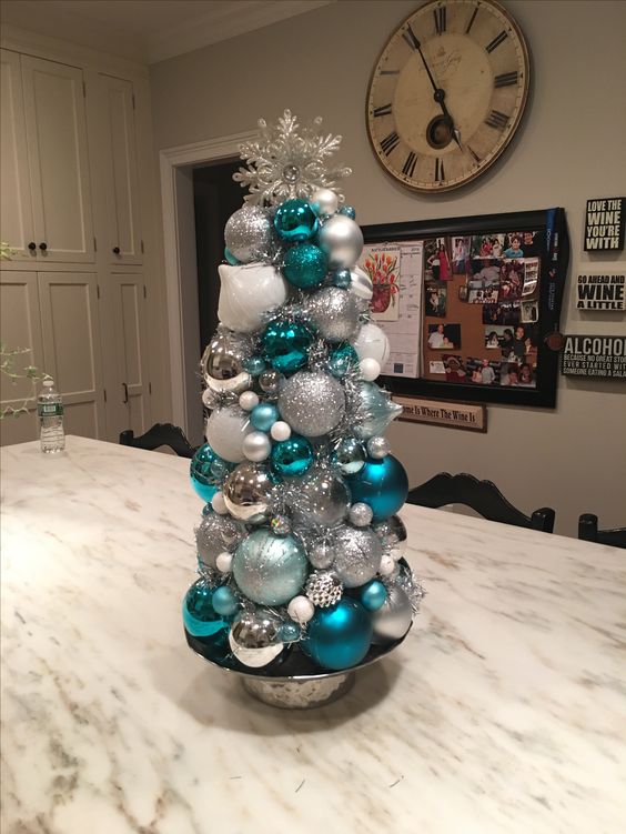 a tabletop Christmas tree made of white, white and blue Christmas ornaments, with a silver snowflake on top