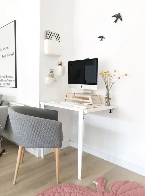 a working nook with a two leg desk, a grey chair, a PC on a stand for more comfort and a series of box like shelves