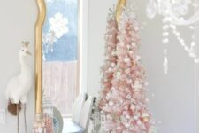 36 a small vintage pink Christmas tree decorated with silver and white ornaments, with some decor under it and a silver star on top