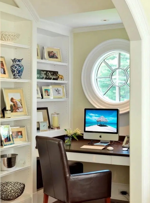 an awkward nook with a porthole window, built-in shelves, a built-in desk and a leather chair is a cool productive oasis