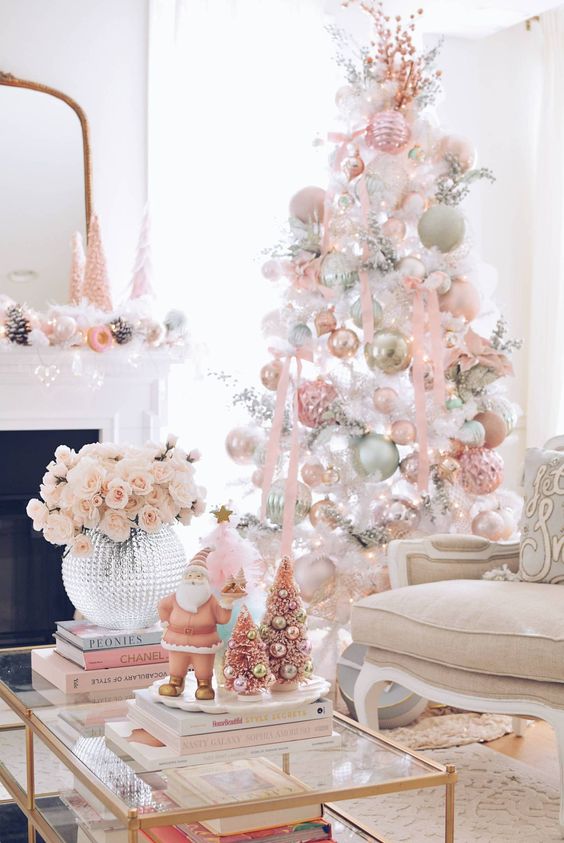 a white Christmas tree decorated with pastel pink, green and white ornaments, pink ribbon and pink branches on top