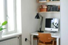 42 a small nook by the window with a white desk and some suspended shelves, a plywood chair and a black table lamp