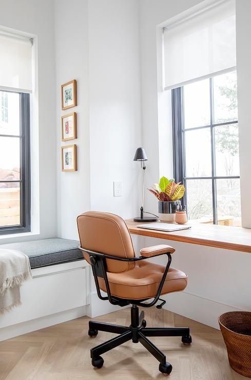 a windowsill turned into an office nook with an amber leather chair and a potted plant, a small gallery wall