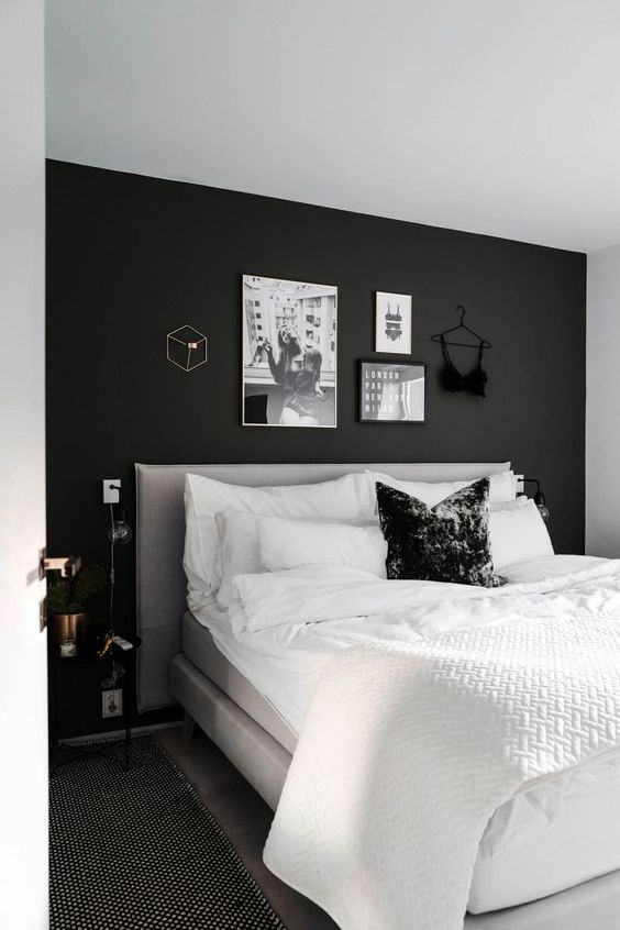 a Scandi bedroom with a black accent wall, a neutral bed with neutral bedding, a gallery wall over the bed