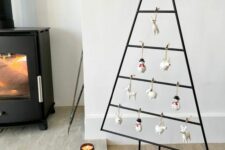 a black metal frame Christmas tree with animal and snowman-shaped ornaments for a touch of fun is a super cool idea